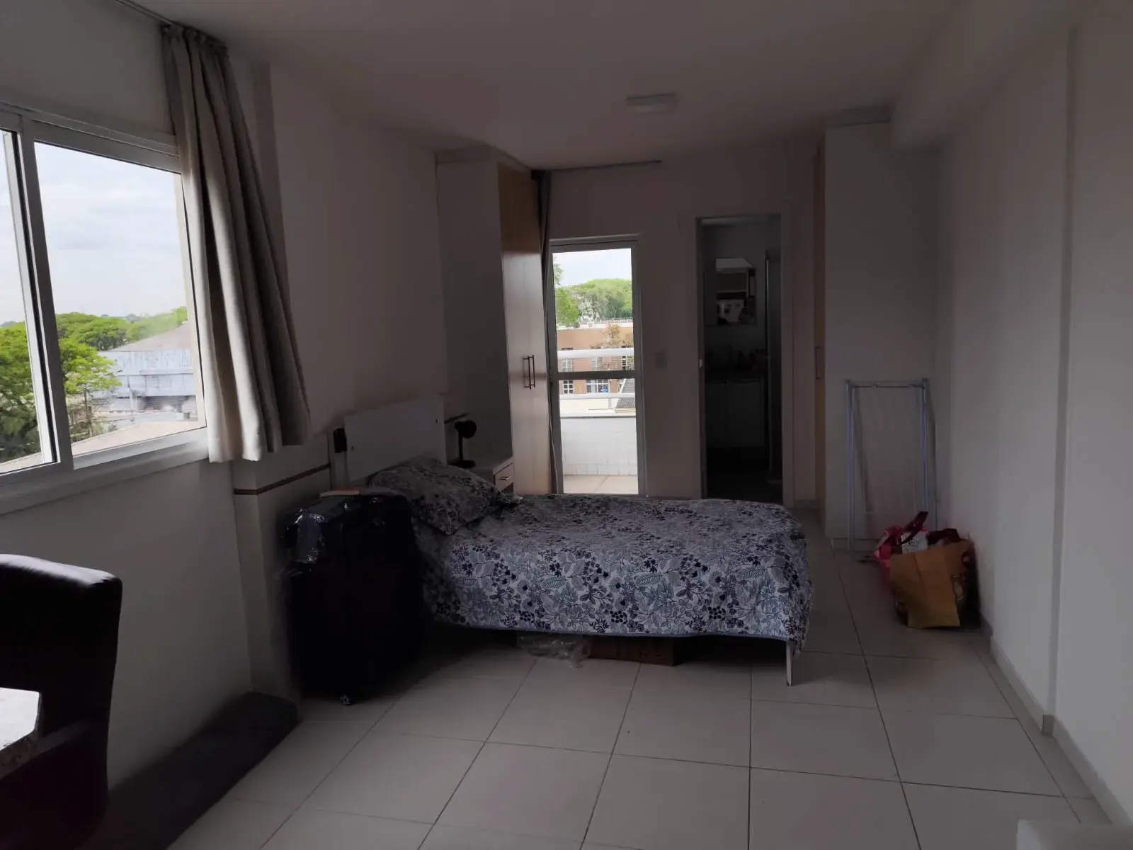 Dormitório amplo com janela e vista da cidade